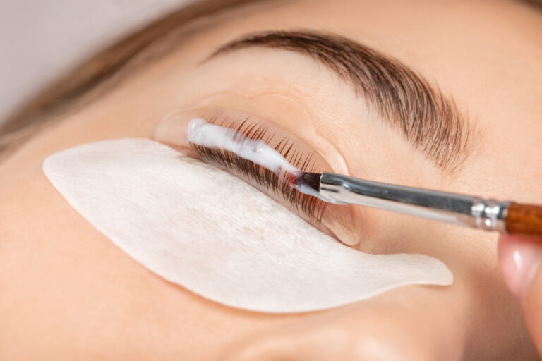 Make-up artist makes the procedure of lamination and dyeing of eyelashes to a beautiful woman in a beauty salon. Eyelash extensions